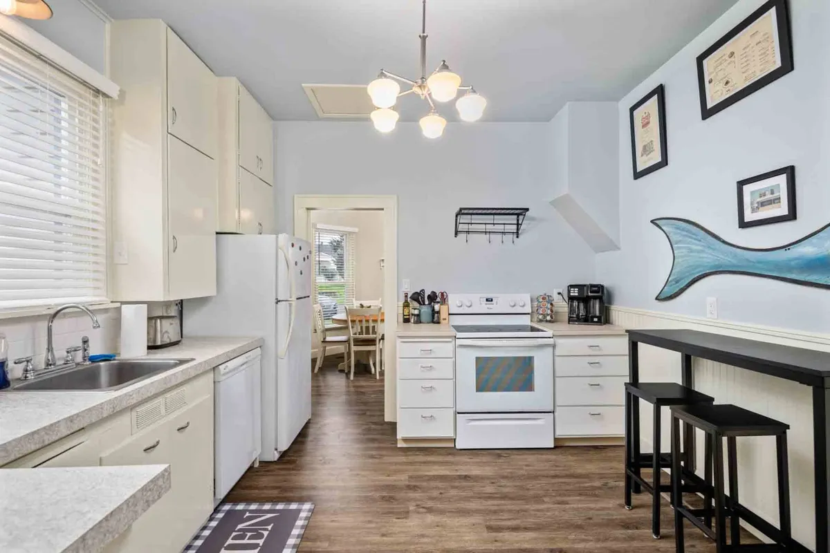 A cheerful kitchen scene with a view of the kitchen countertop, stove, eye-catching blue fish decor, and bar stools set up for casual conversation or snacks. The setting is bright and lively, suggesting a space for both cooking and socializing.