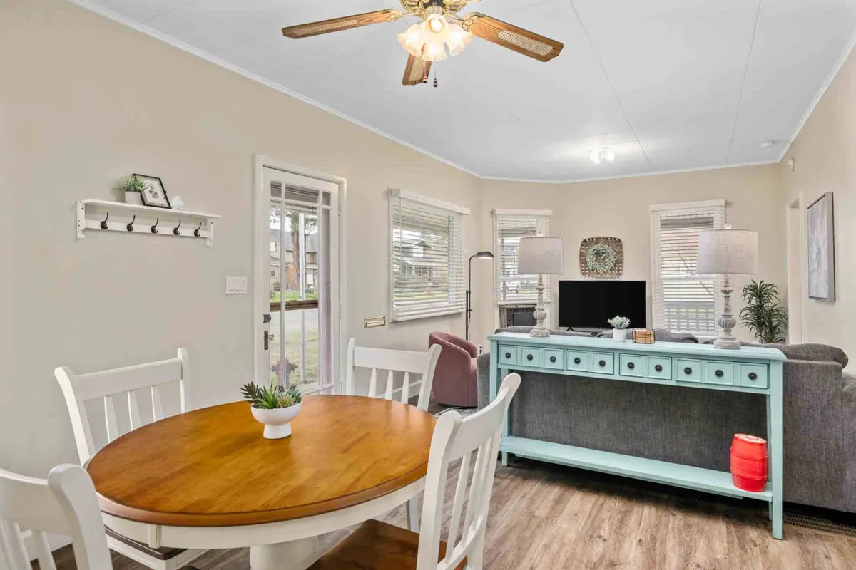 A warm and welcoming dining area featuring a round wooden table, turquoise sideboard, comfortable seating, and elegant light fixtures. The space feels intimate yet spacious, perfect for casual meals, conversations, or celebrating special moments.