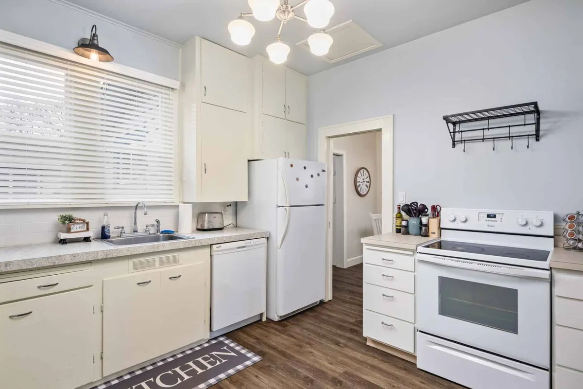 A bright, inviting kitchen featuring modern appliances, a spacious countertop ideal for meal preparation, and a window with blinds allowing in natural light. The scene subtly evokes the feeling of home-cooked meals and togetherness, with plenty of functional space for cooking or baking.