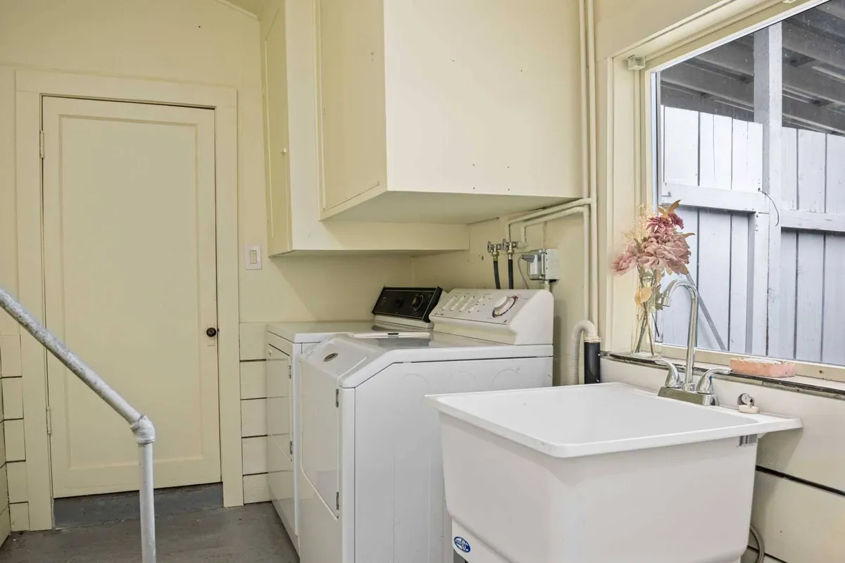 A utility room with a washing machine, dryer, and a window overlooking the outdoors. The space feels practical and welcoming, with views that hint at the green surroundings. It highlights the comfort of returning to a well-equipped home after outdoor adventures.